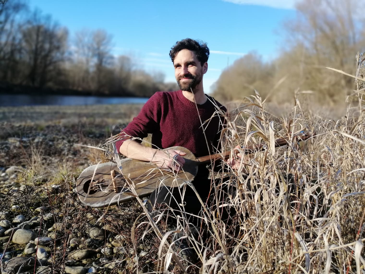 portret Iztoka Korena s primitivnim brenkalom v rokah in stoječega v ločju.