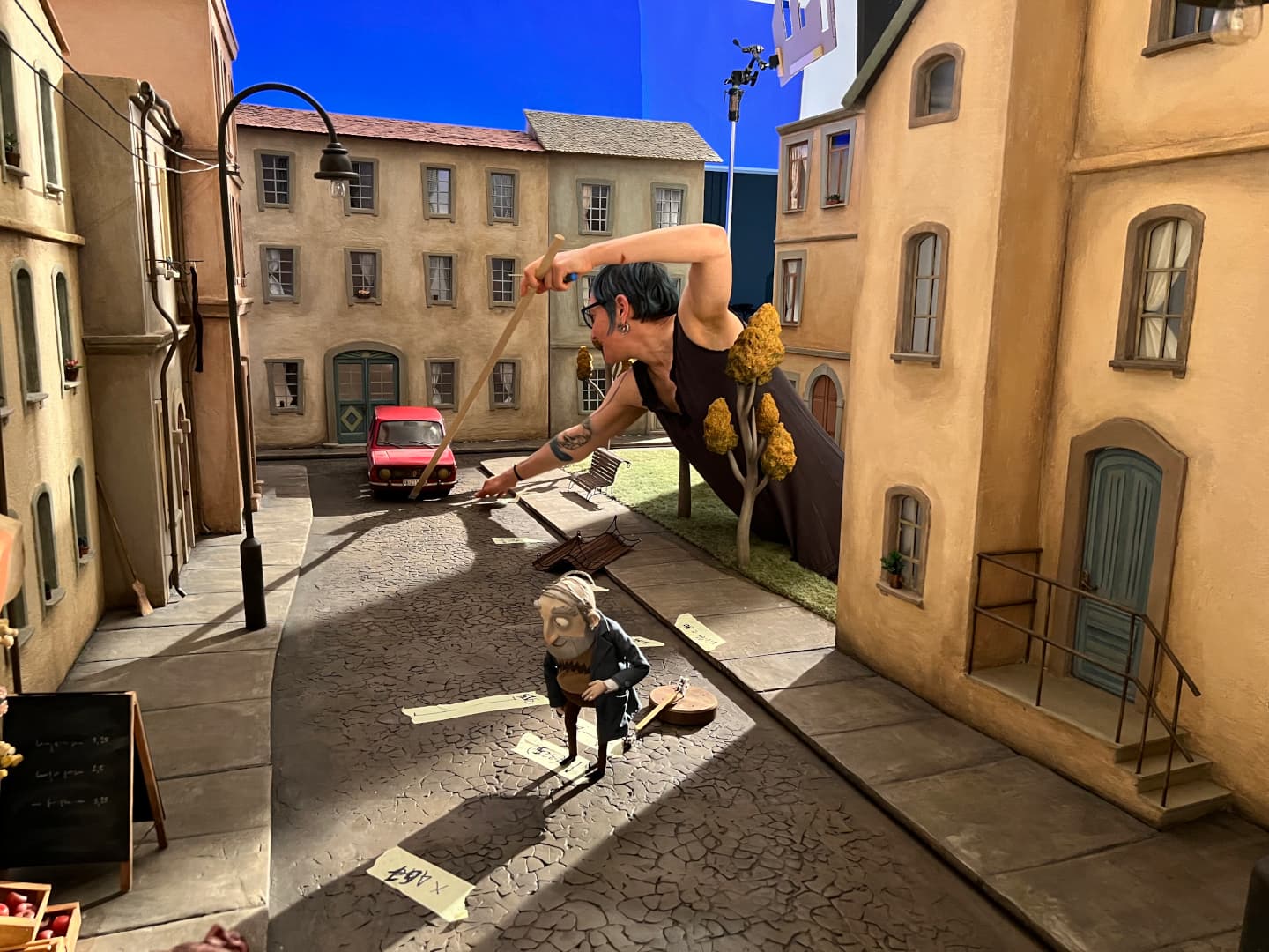 Na fotografiji so kulise iz filma Zgodbe iz čarobnega vrta. Izza ene od kulis se v sceno sklanja animatorka, ki popravlja lgo avtomobila v sceni.