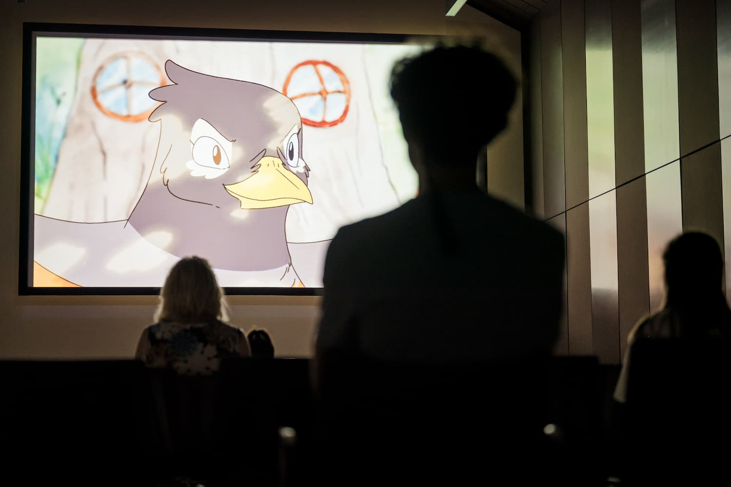 senca človeka pred platnom, na katerem se vrti risanka